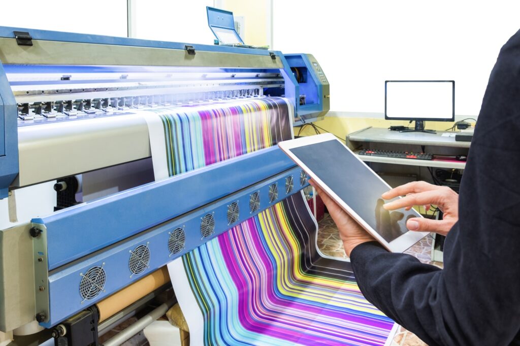 Hand using tablet control with inkjet printer printing multicolor vinyl